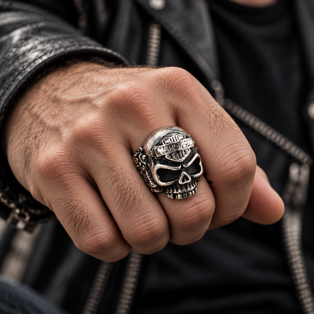 Close-up of clenched fist wearing stainless steel gothic biker skull ring with leather jacket