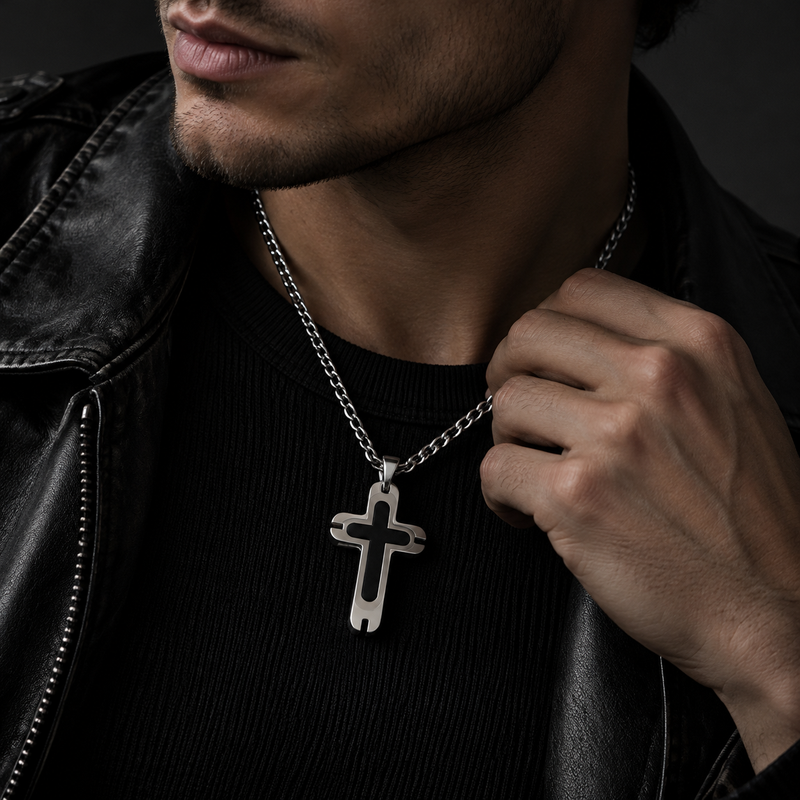 Close-up chest shot of model touching chain wearing men's notched black cross pendant
