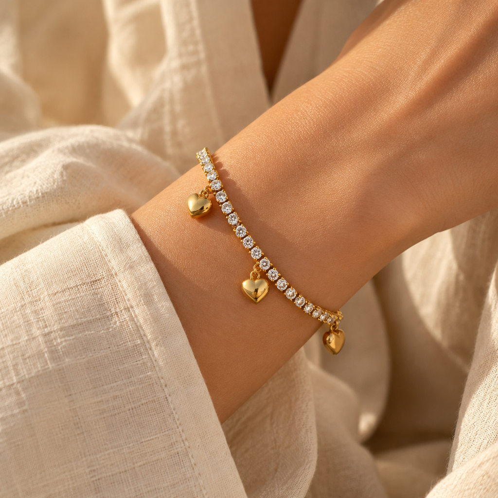 Lifestyle wrist shot of the romantic heart tennis chain bracelet glistening in natural sunlight paired with a white outfit.
