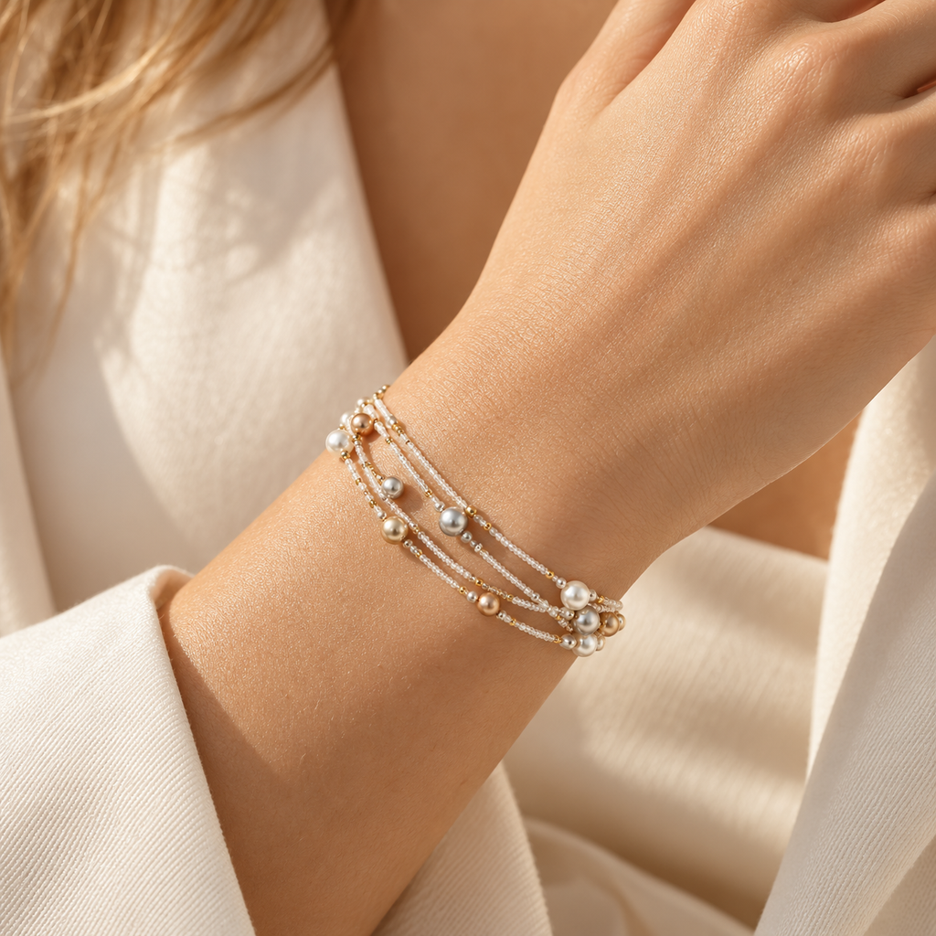 Detailed close-up shot of model wrist wearing layered multicolor pearl beaded bracelet paired with cream blazer
