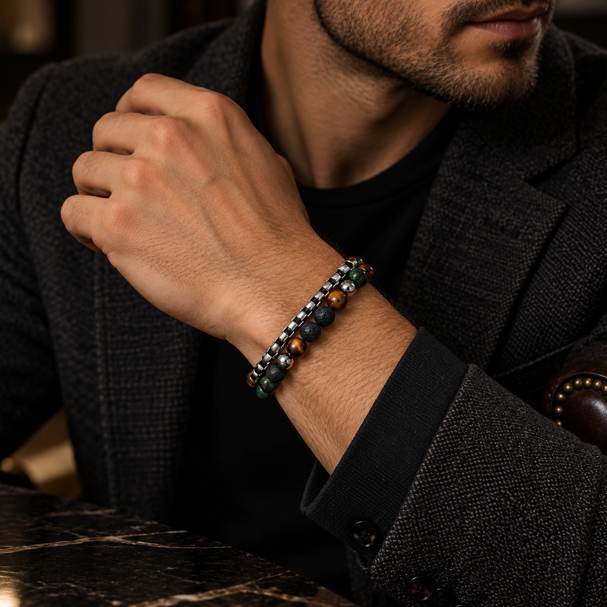 Male wrist wearing stainless steel box chain and natural beaded gemstone bracelet with blazer
