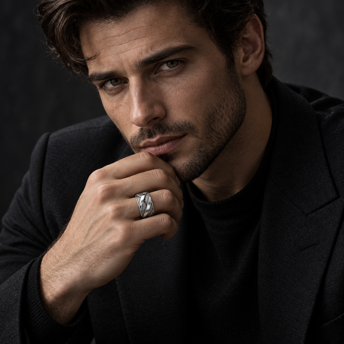 Handsome male model in black blazer touching chin wearing futuristic mesh band ring
