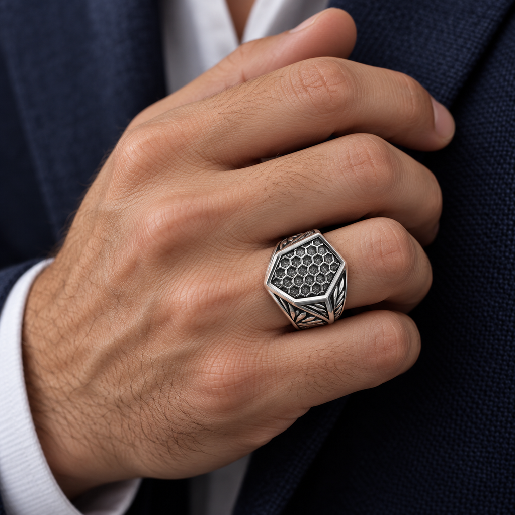 Close-up of male hand touching navy suit jacket wearing hexagonal honeycomb signet ring
