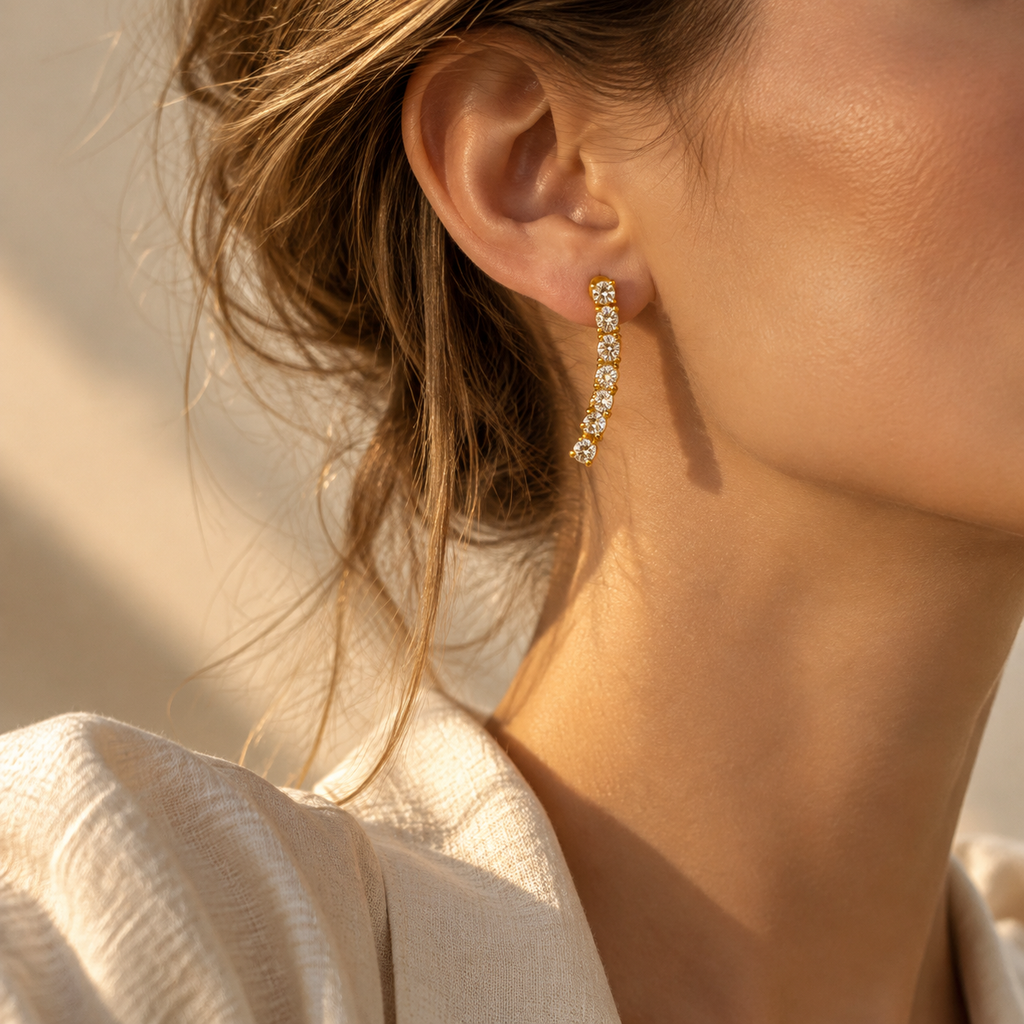 Side profile of woman wearing curved line drop earrings set with brilliant clear CZ crystals in warm sunlight
