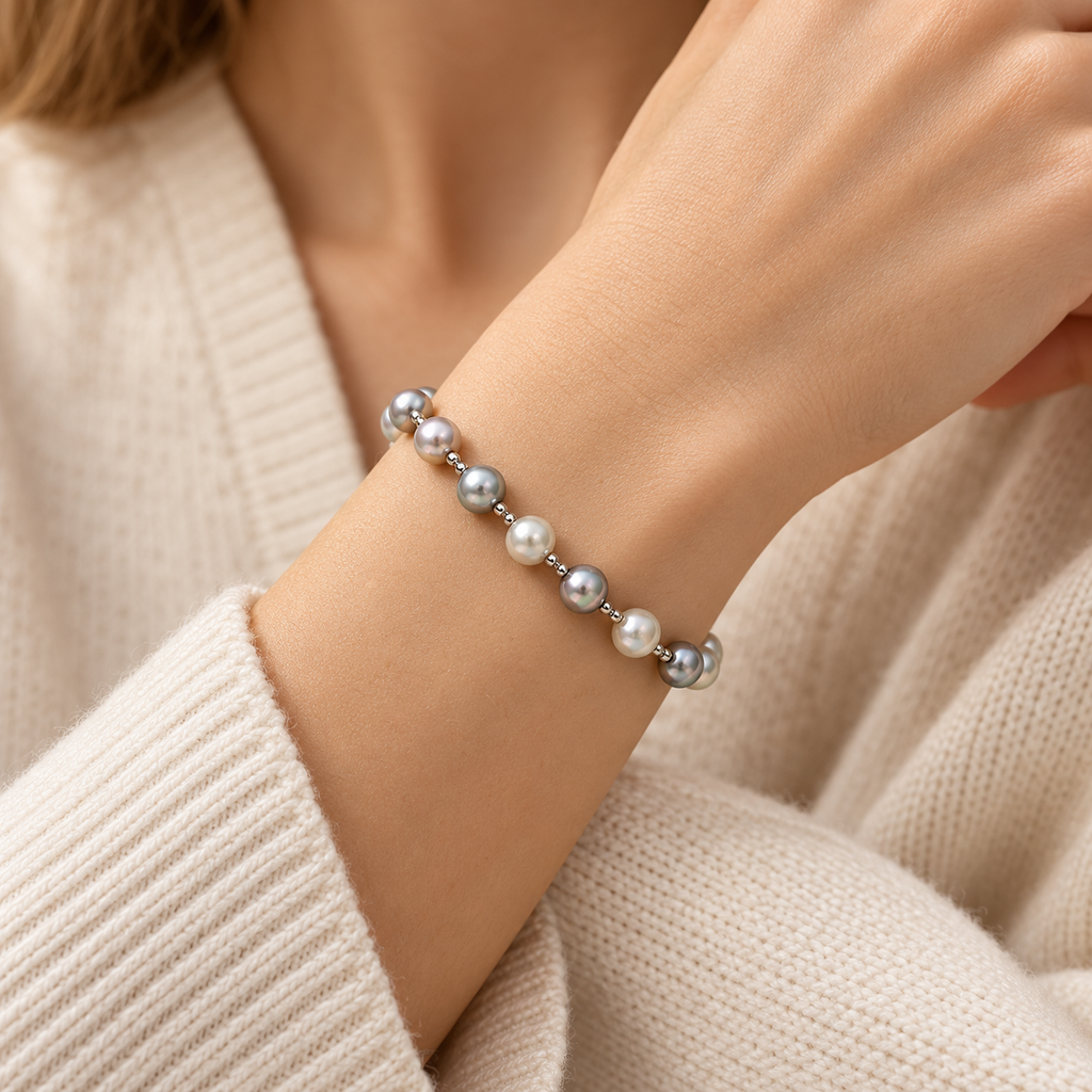 Close-up of woman wearing multi-color grey pearl station beaded bracelet with knit sweater
