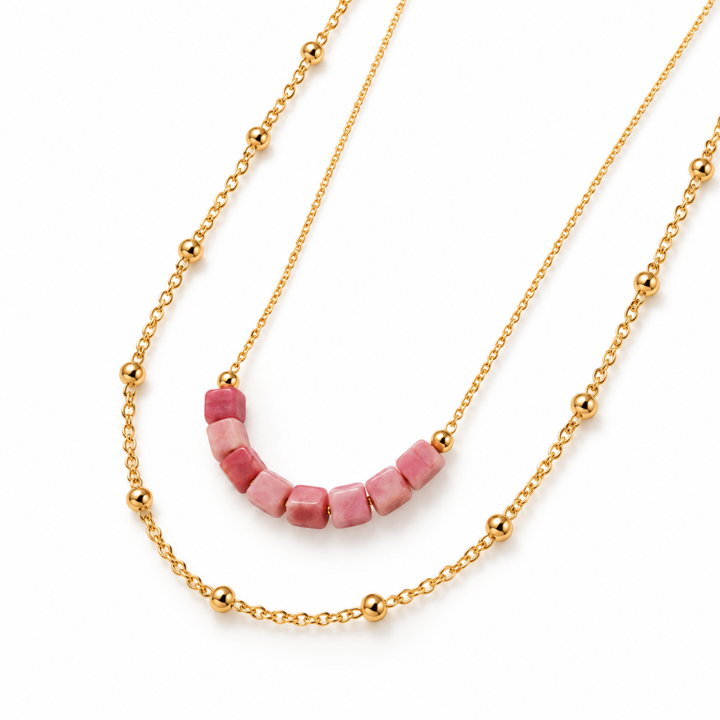 Overhead product flat lay of the double-layer gold chain necklace highlighting the faceted pink rhodonite cubes and gold beads.
