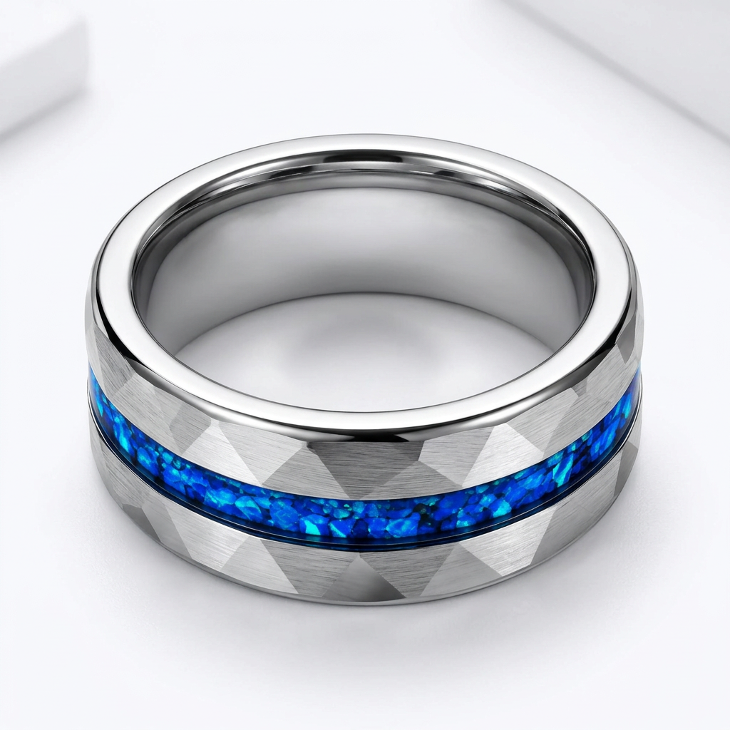 Faceted stainless steel wedding band with vibrant crushed blue opal inlay on jewelry block
