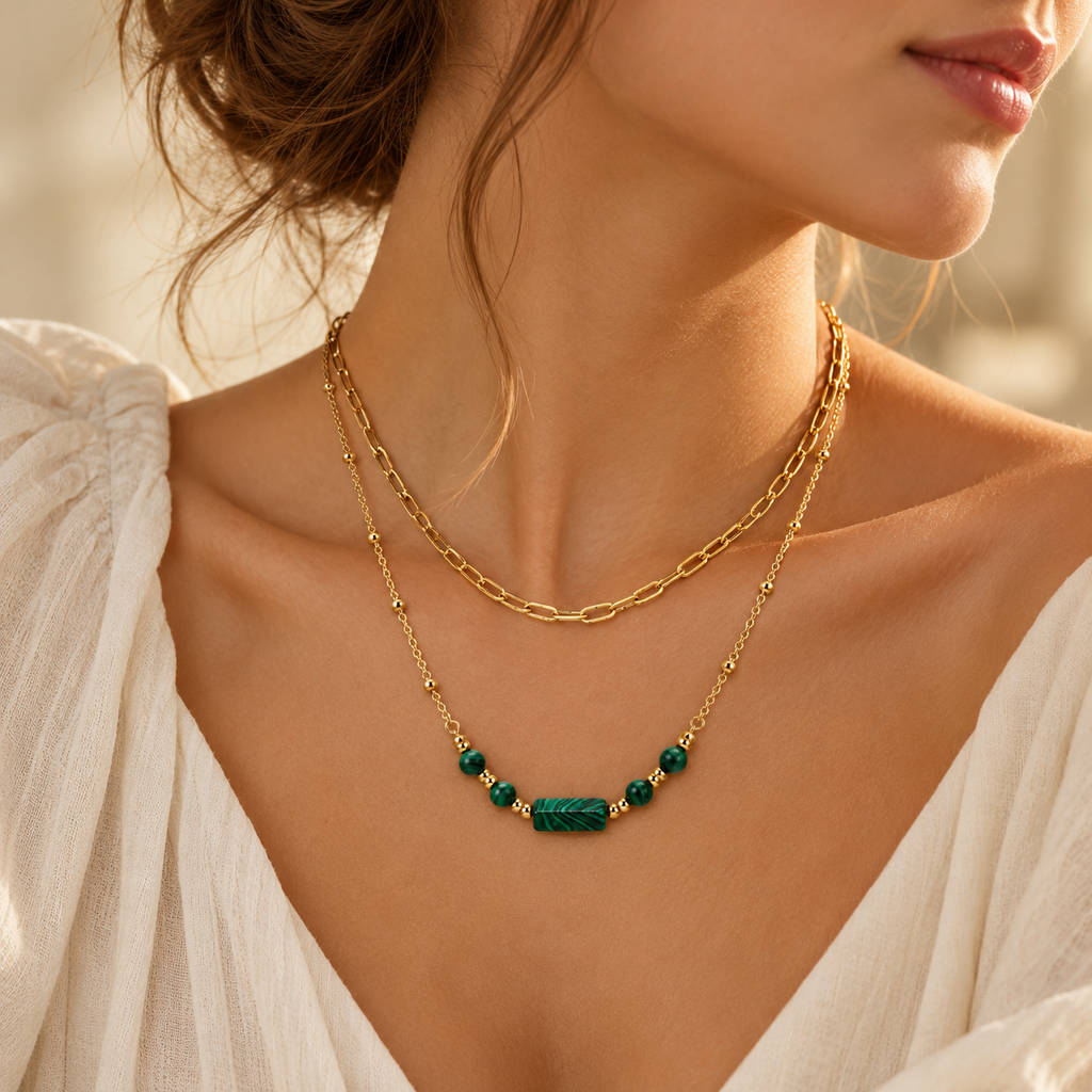 Lifestyle portrait of a woman wearing the trendy pre-layered gold paperclip chain and green gemstone necklace.
