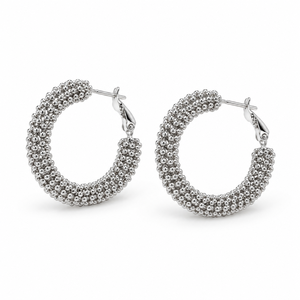 Pair of chunky silver beaded caviar texture hoop earrings on white background
