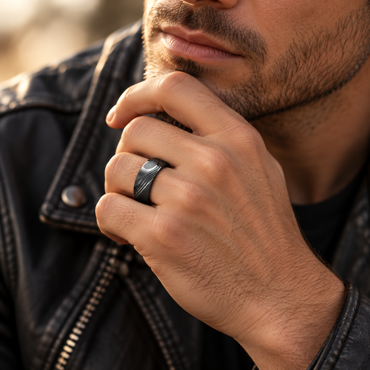 Male model wearing black brushed stainless steel band ring while touching chin
