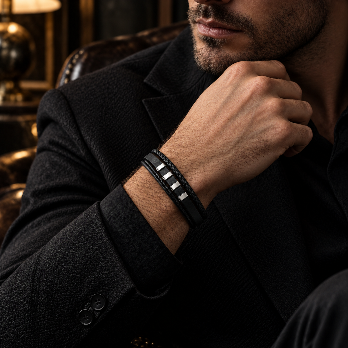 Male wrist resting on tailored blazer showing segmented steel bar leather bracelet
