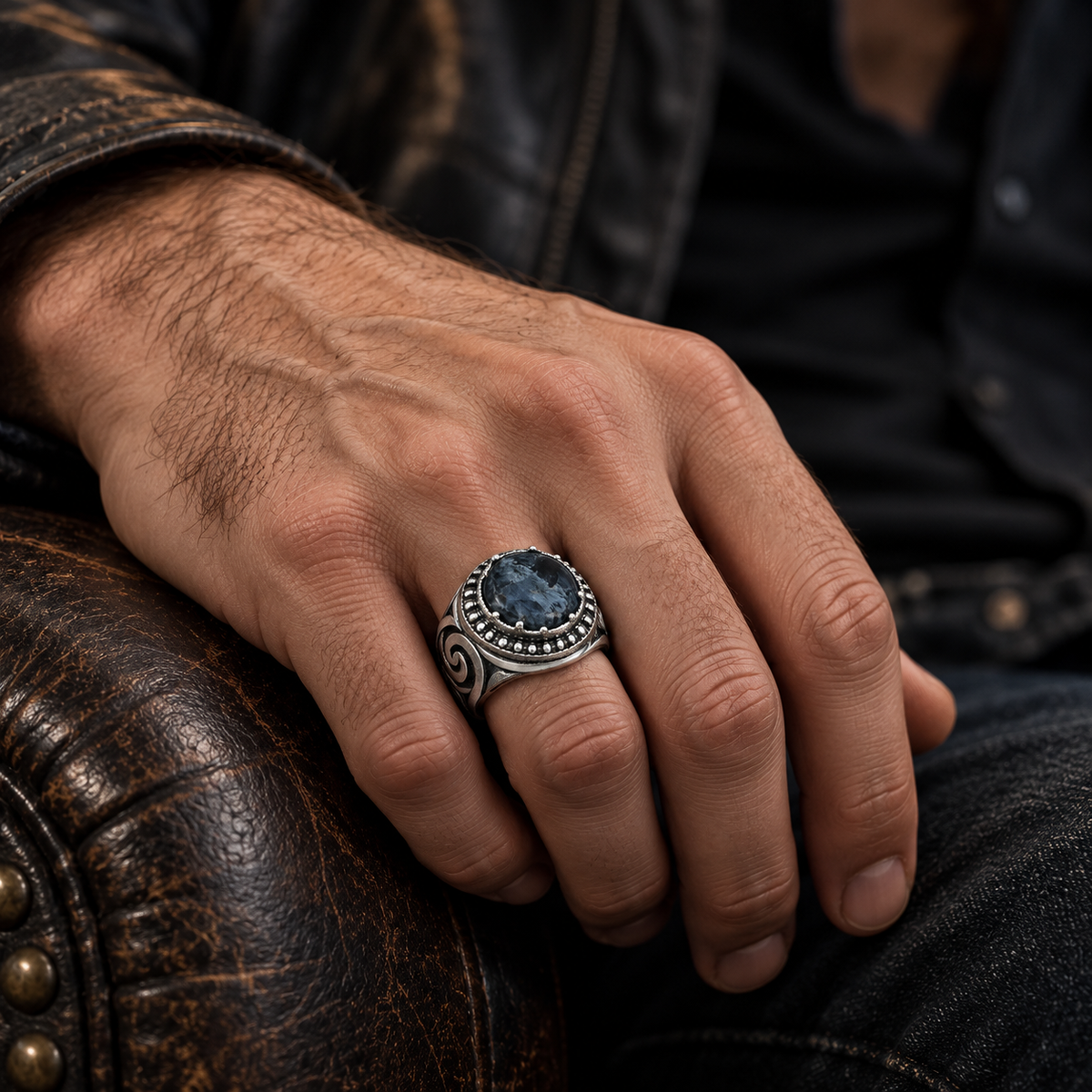 Male hand on vintage leather armchair wearing natural blue stone signet ring
