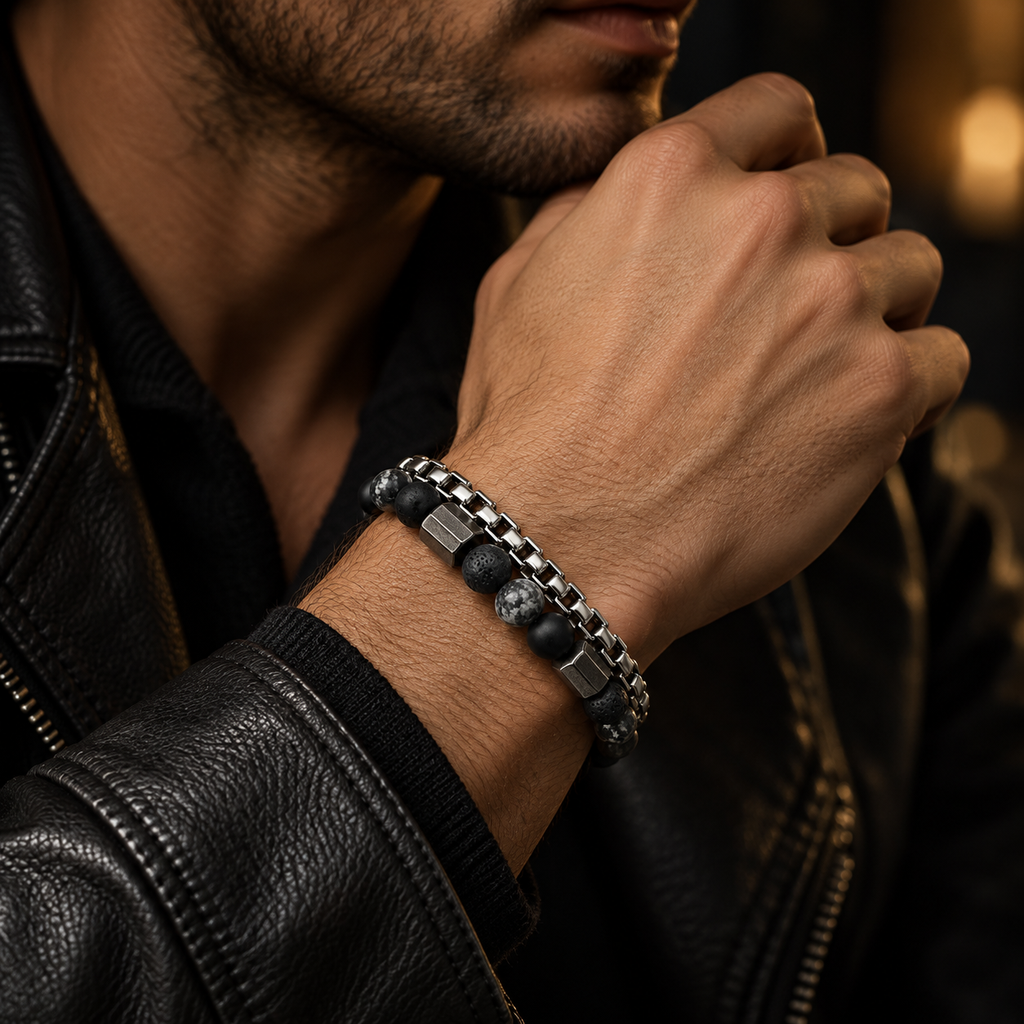 Male wrist wearing stainless steel box chain and black stone beaded bracelet with leather jacket
