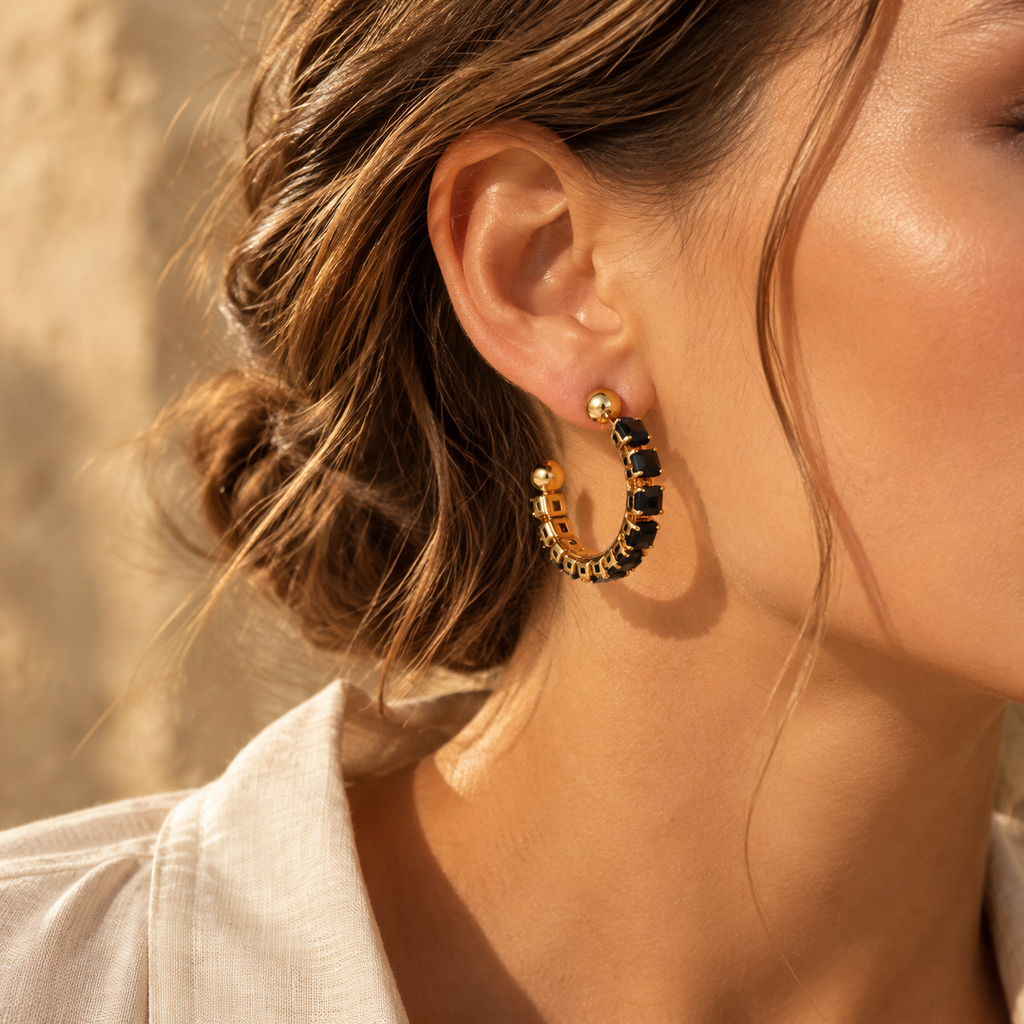 Side profile of woman wearing bold 18K gold plated open hoop earrings embellished with sparkling black cubic zirconia crystals
