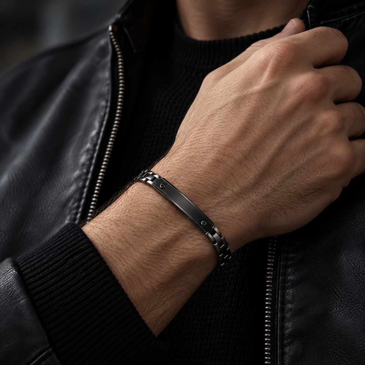Close-up wrist view of men's black motorcycle link bracelet on black jacket
