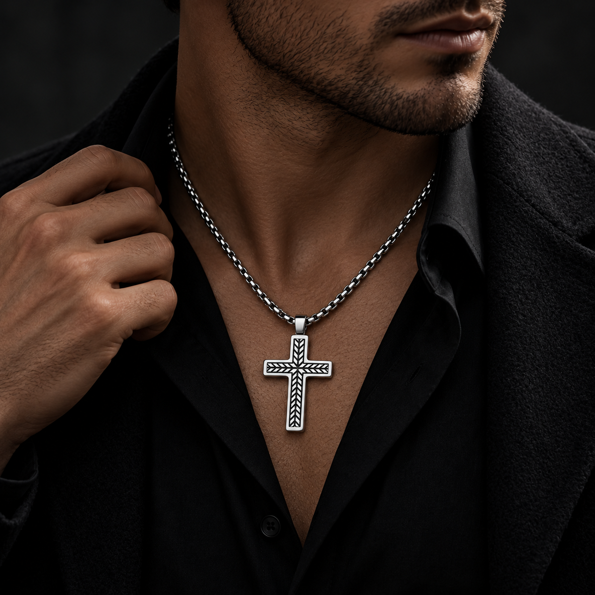 Model wearing men's engraved herringbone cross necklace with black coat and button-down shirt
