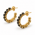Pair of women's chunky gold open C-hoop earrings set with faceted square black zircon stones on white background
