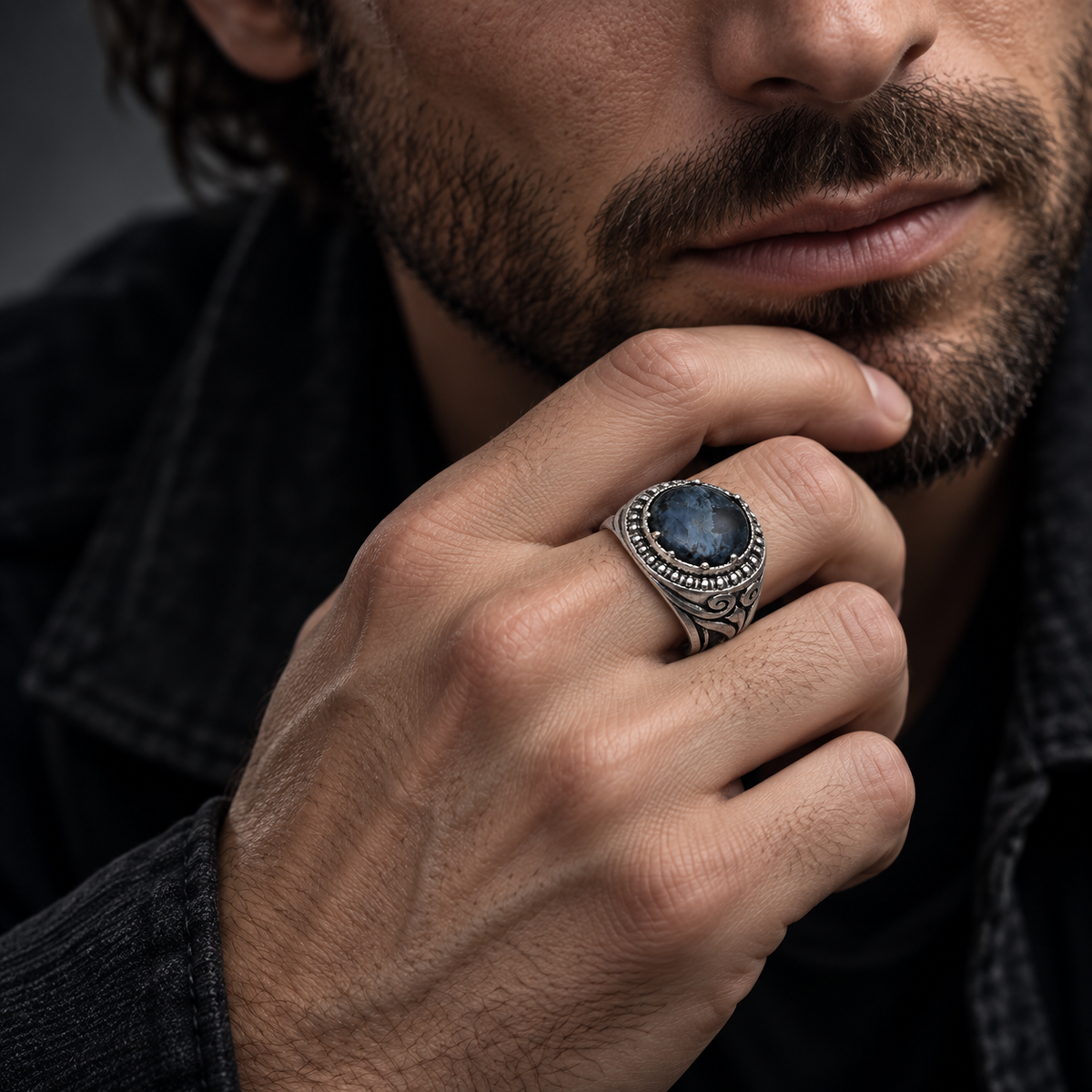 Male model in black denim touching chin wearing Men's blue sodalite gemstone ring
