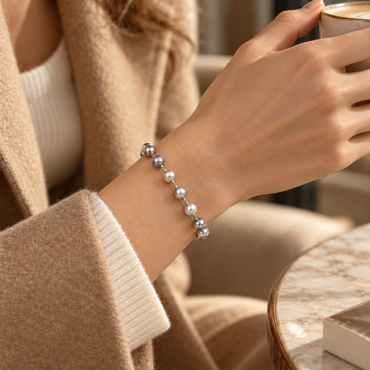 Lifestyle shot of woman wearing elegant grey freshwater pearl bracelet while holding coffee cup
