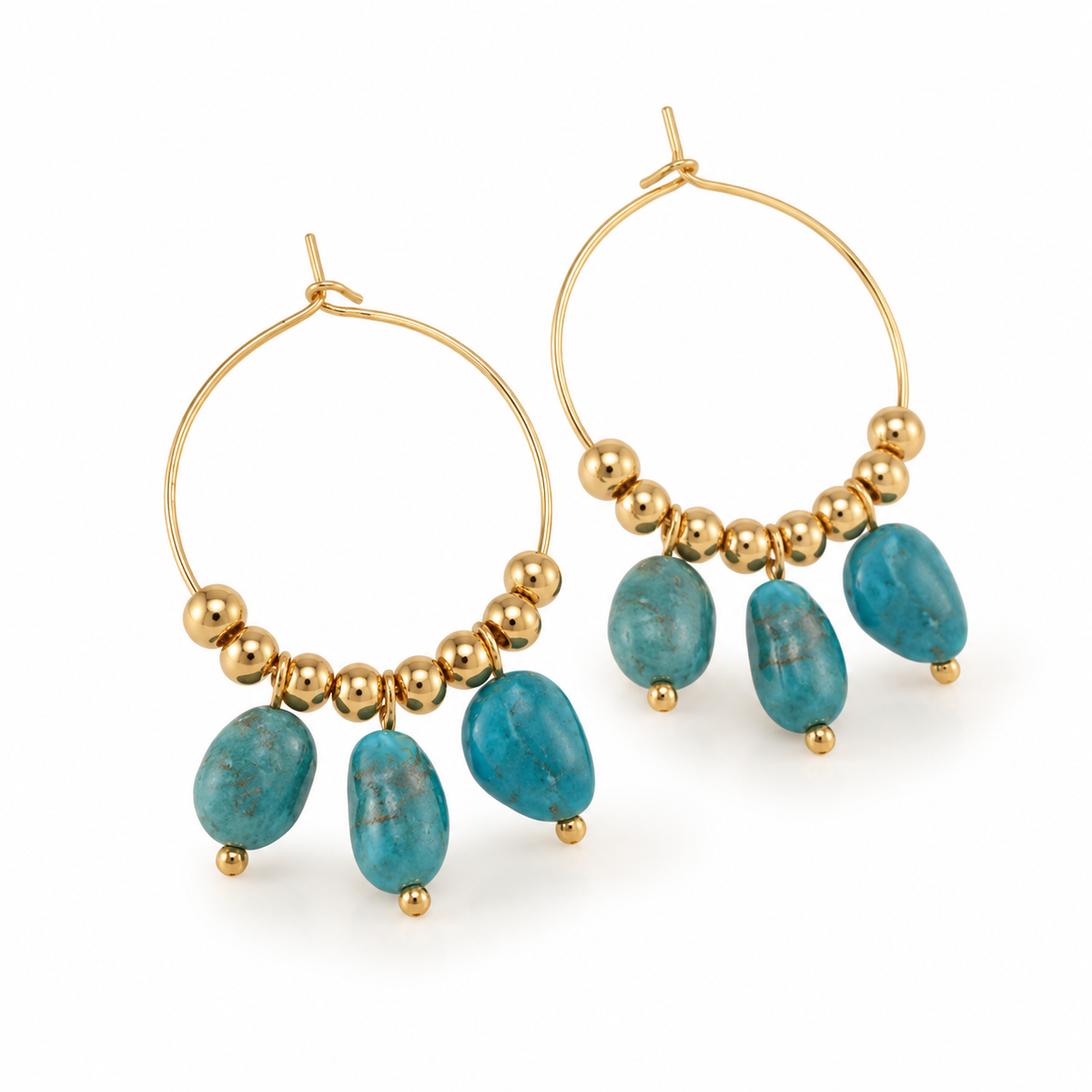 Angled studio shot of two gold hoop earrings with polished spacer beads and vibrant turquoise nugget pendants on white surface

