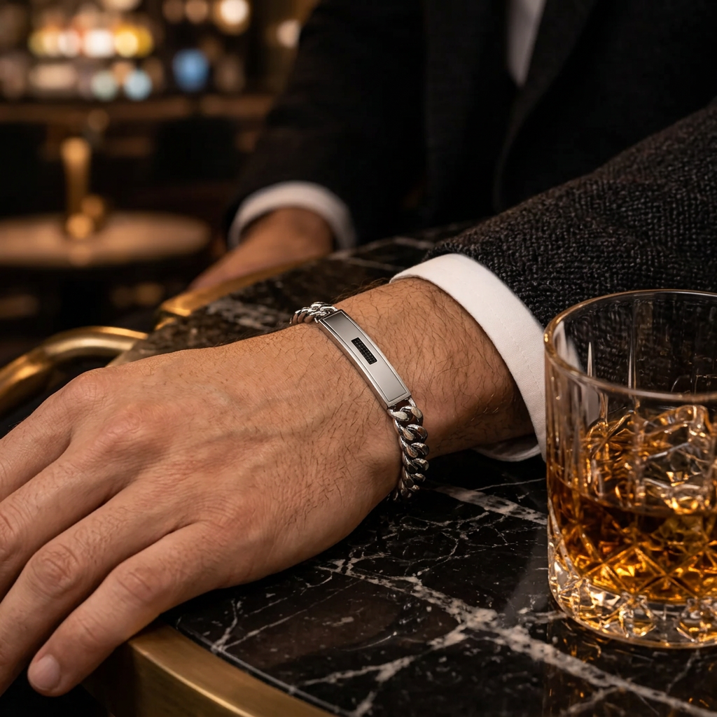 Close-up wrist view of men's Cuban link black CZ ID bracelet on marble bar table
