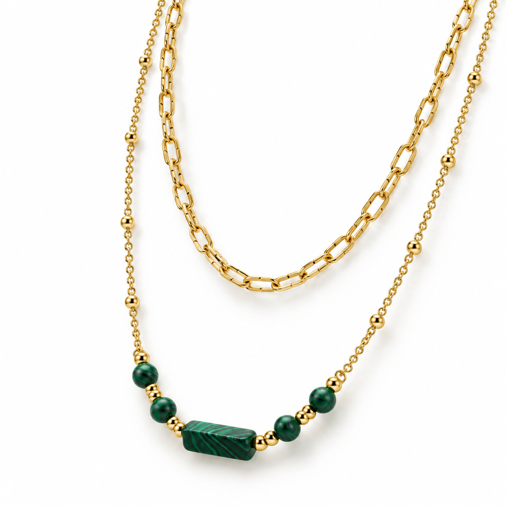 Detailed product flat lay of the layered gold chain necklace highlighting the engraved green malachite cylinder bar and bead accents.
