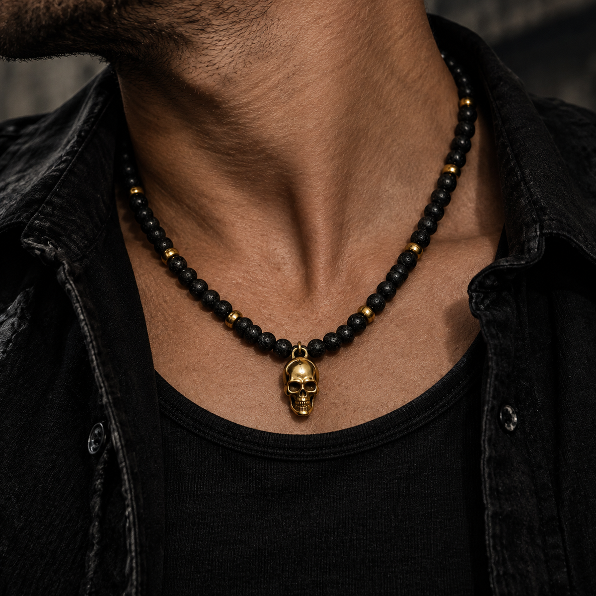 Model wearing men's gold skull lava stone beaded necklace with black jacket
