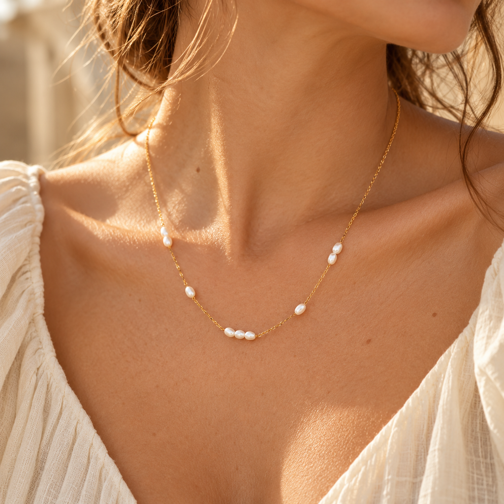 Detail view of women's gold pearl choker necklace accentuating the collarbone
