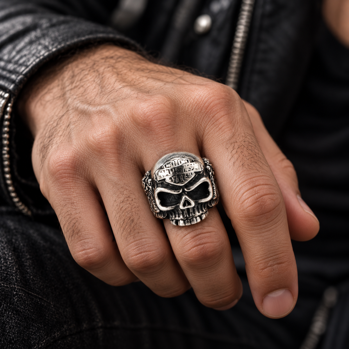 Angled hand shot of heavy vintage skull ring in stainless steel resting on denim