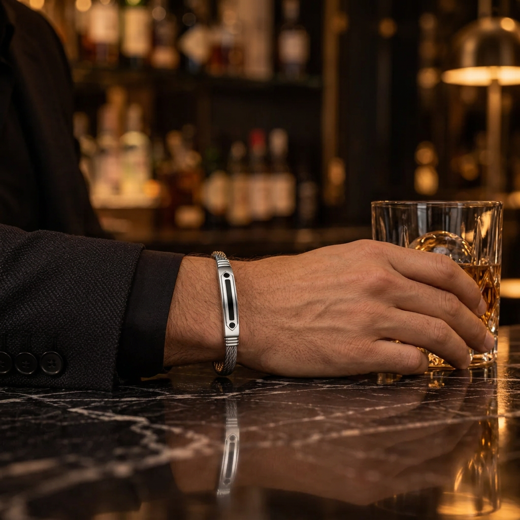 Close-up wrist view of men's cable bracelet with black CZ accents on marble bar table

