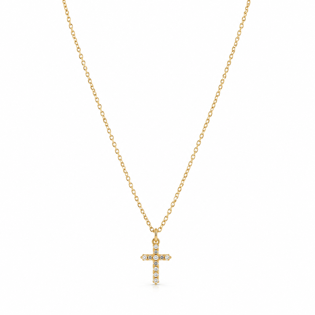 Dainty gold cable chain necklace with micro CZ crystal cross charm against white background
