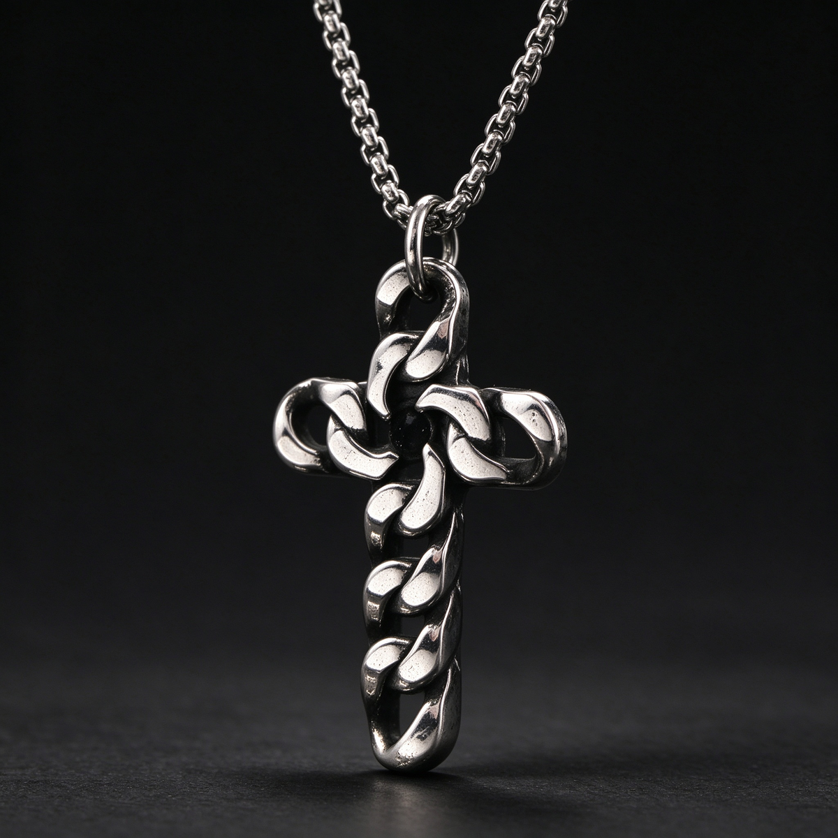Studio macro close-up of men's interlocking curb chain cross pendant on black background
