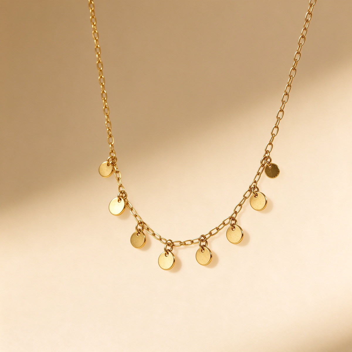 Detailed macro shot of shimmering link chain and polished round disc charm drops in 18K gold