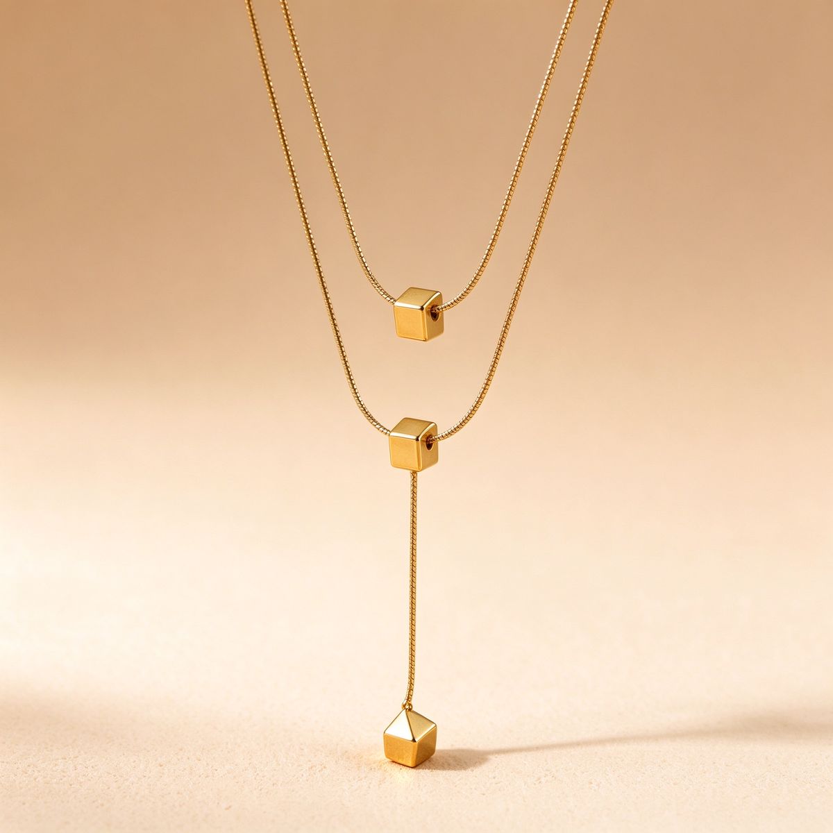 Close up view of 18k gold plated geometric cube beads on double snake chain necklace
