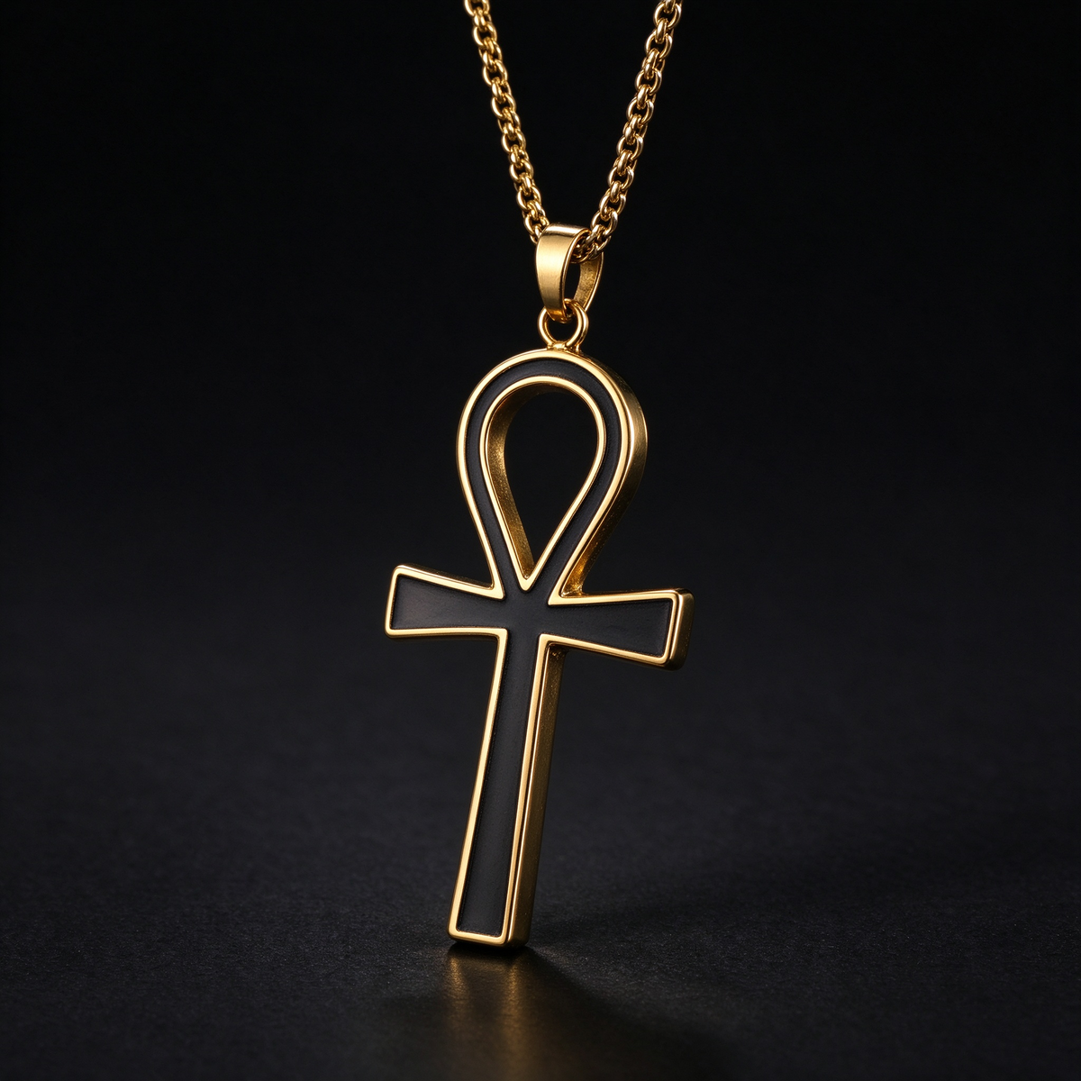 Detailed studio close-up of men's gold Ankh cross pendant with black inlay on dark background
