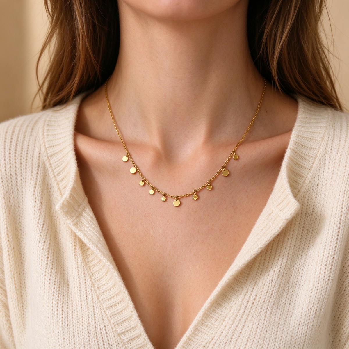 Model wearing gold hanging disc charm choker necklace with white knit top