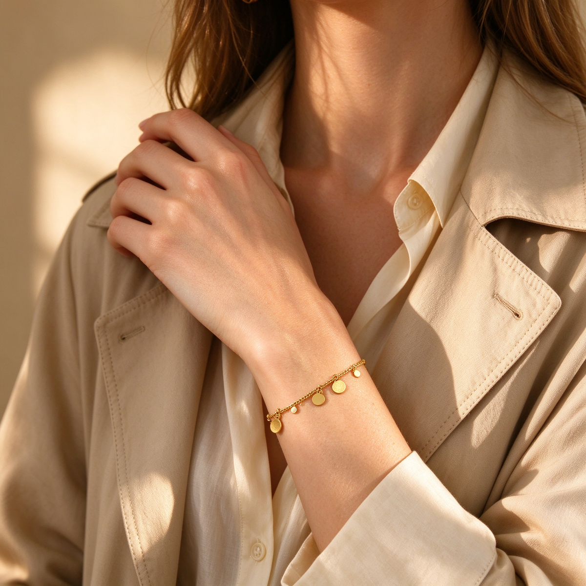 Fashion lifestyle model in beige trench coat wearing 18K gold plated hanging disc bracelet
