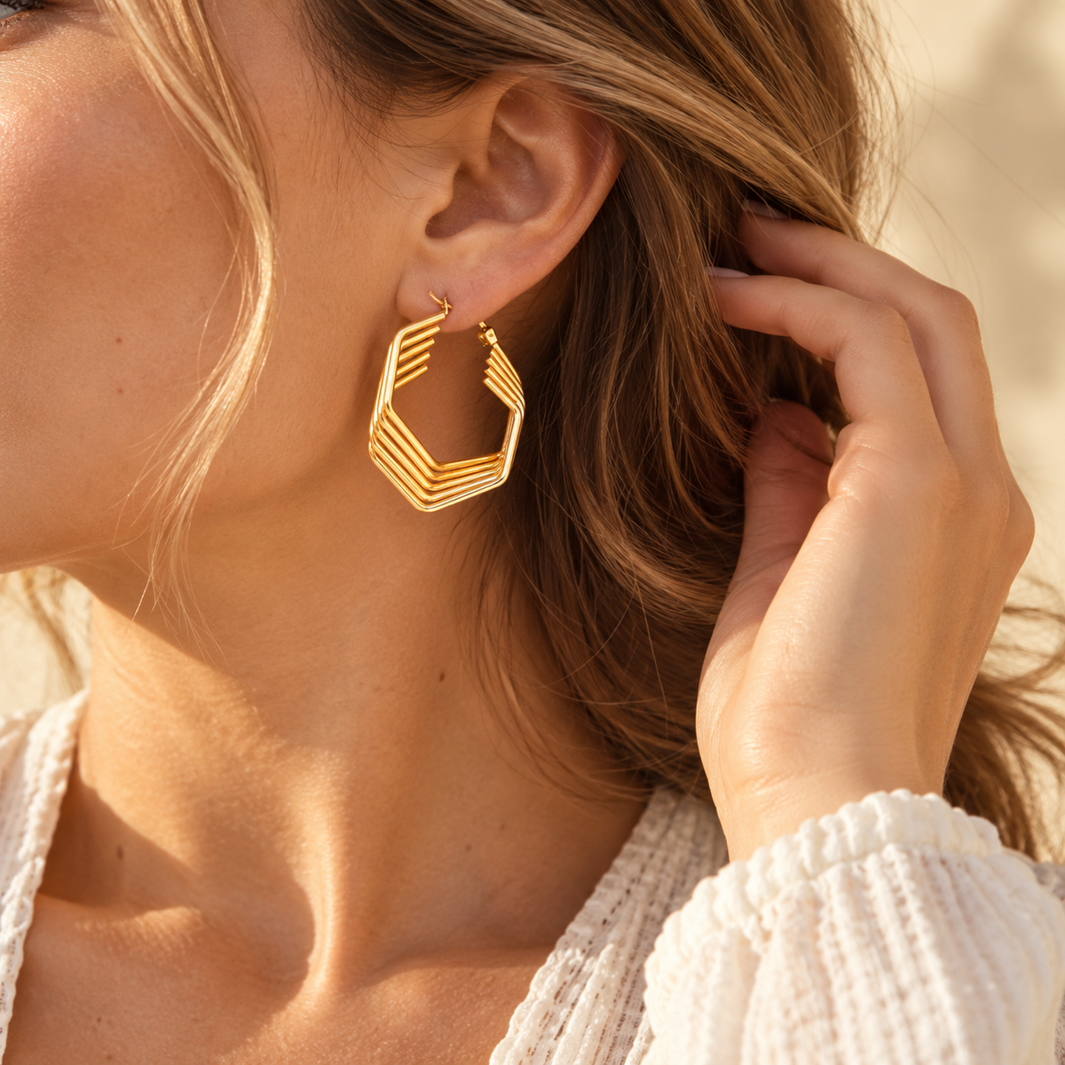 Model wearing 18K gold plated multi-strand geometric hexagonal wire hoop earrings in warm sunlight

