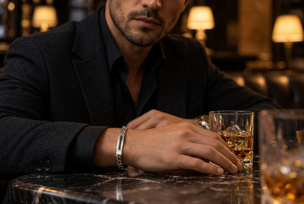 Close-up wrist view of men's Cuban link black CZ ID bracelet on marble bar table
