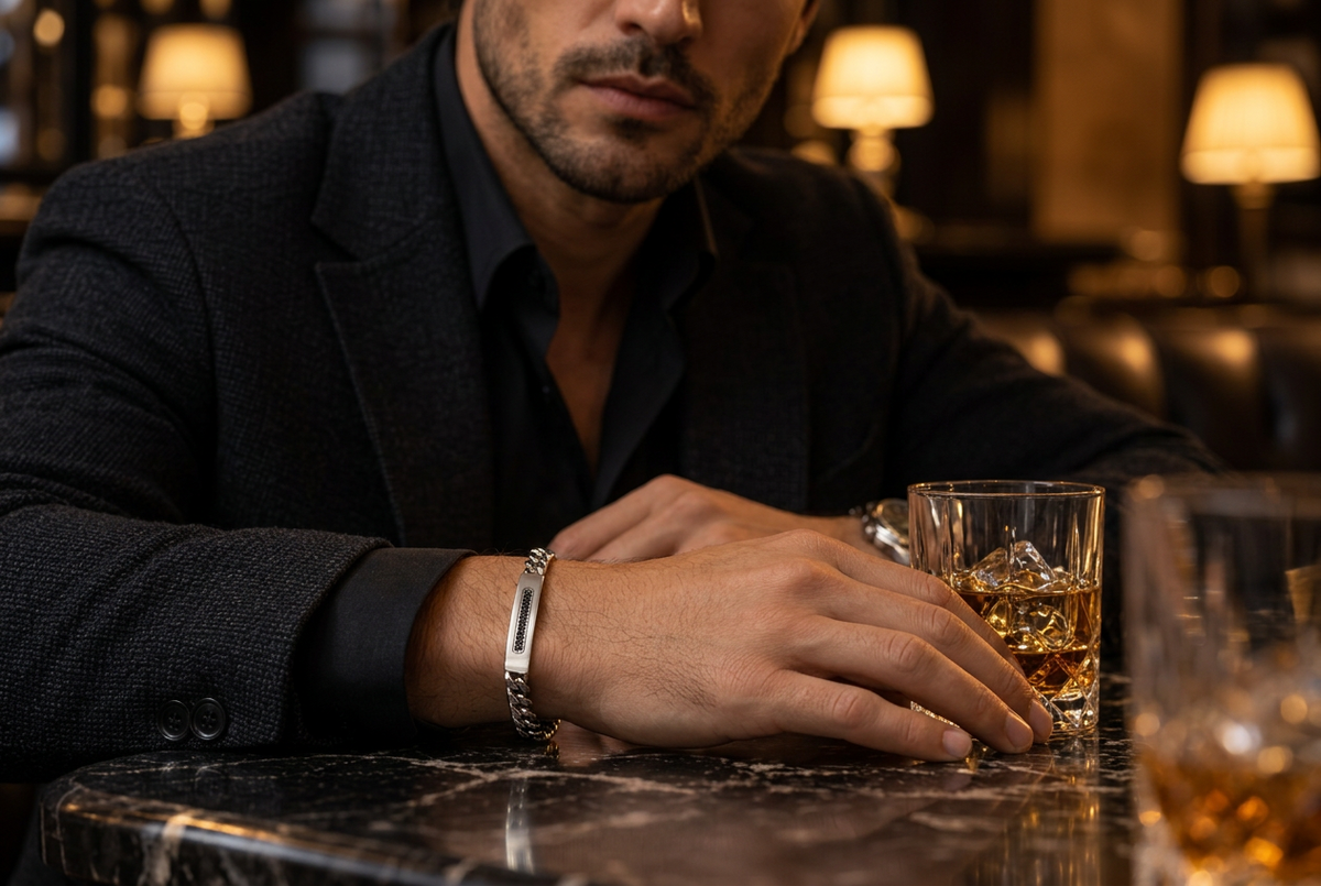 Close-up wrist view of men's Cuban link black CZ ID bracelet on marble bar table
