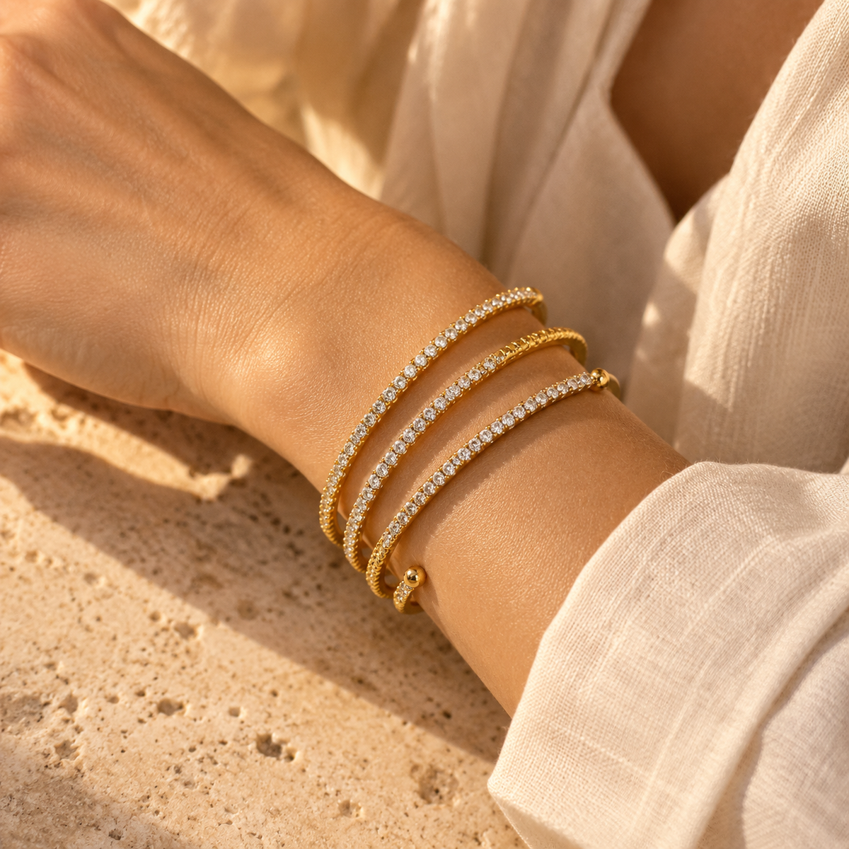 Model wrist shot showcasing the sparkling multi-strand wrap cuff bracelet with round ball ends in warm glowing sunlight.
