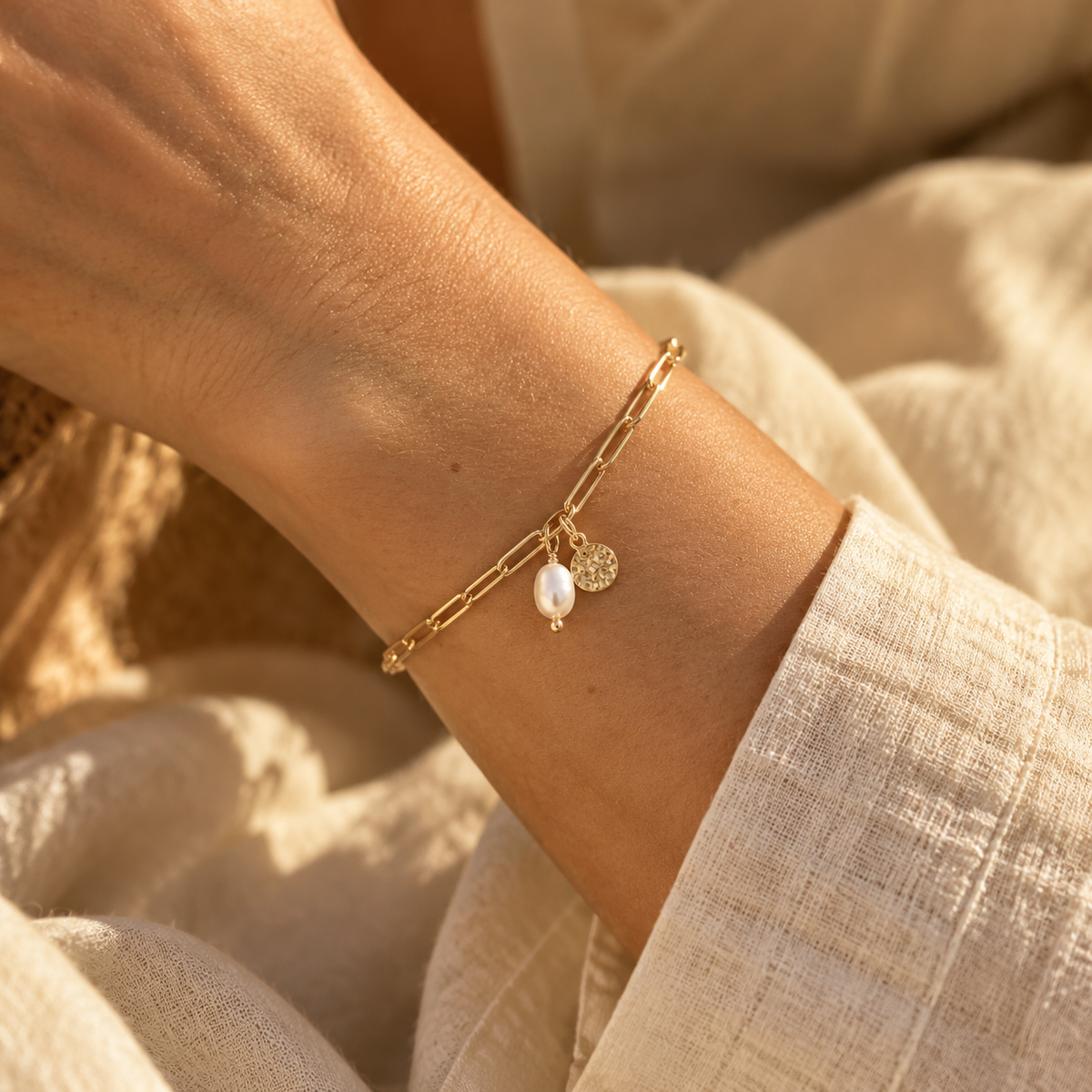 Warm sunlight lifestyle view of woman wearing delicate gold paperclip link bracelet with natural freshwater pearl drop
