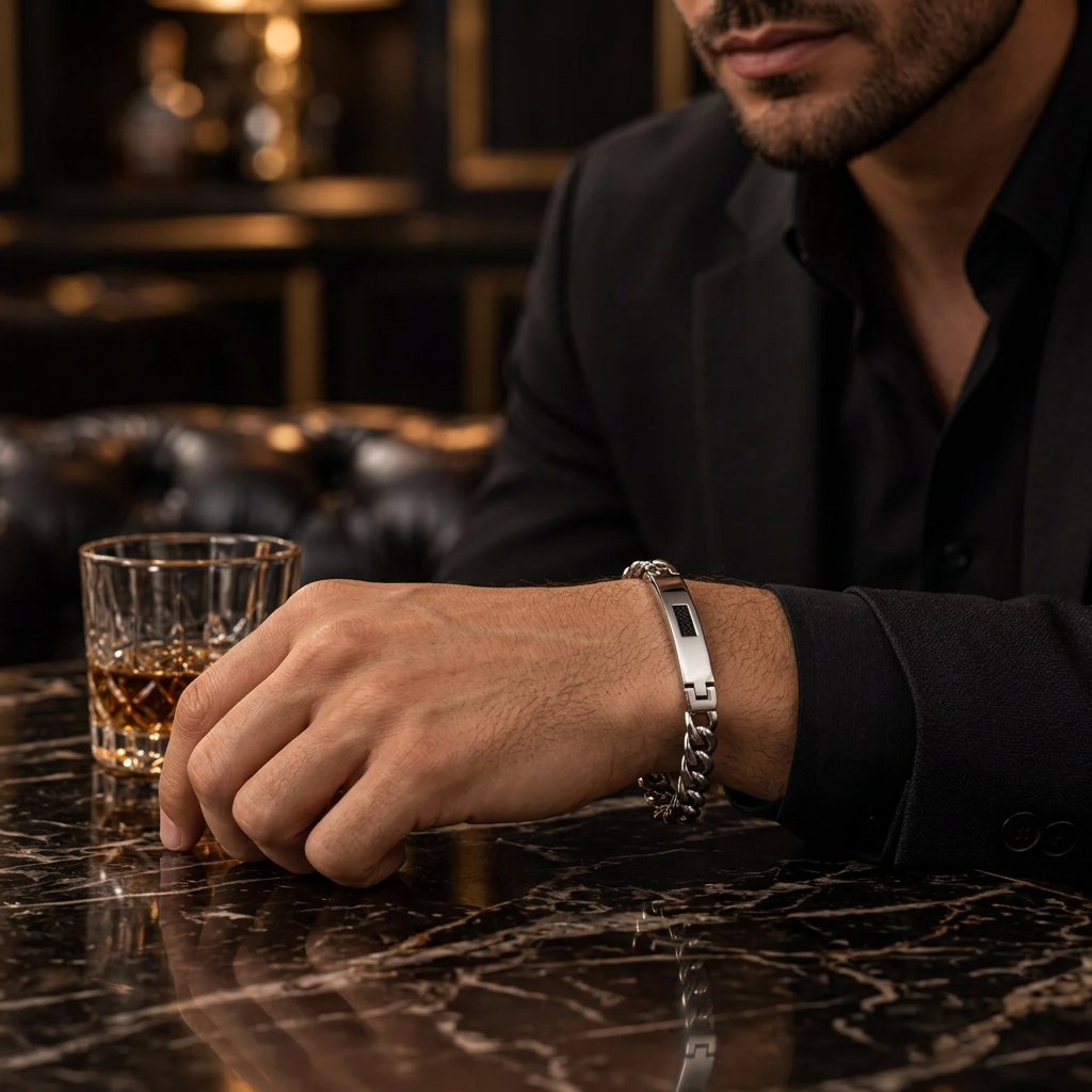 Close-up wrist shot of men's Cuban link ID bar bracelet on marble bar table
