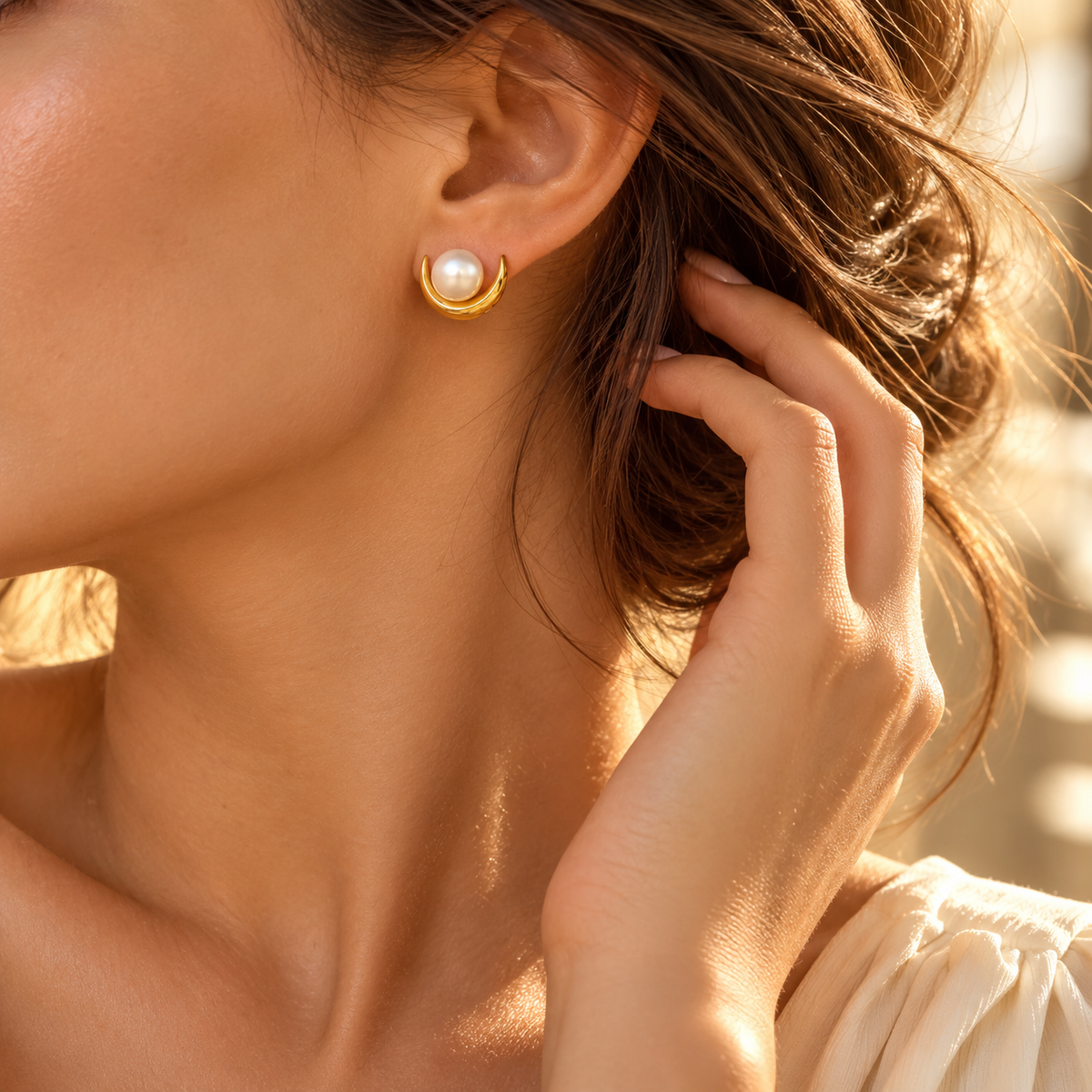 Side profile lifestyle view of woman wearing minimalist gold and pearl crescent post earrings
