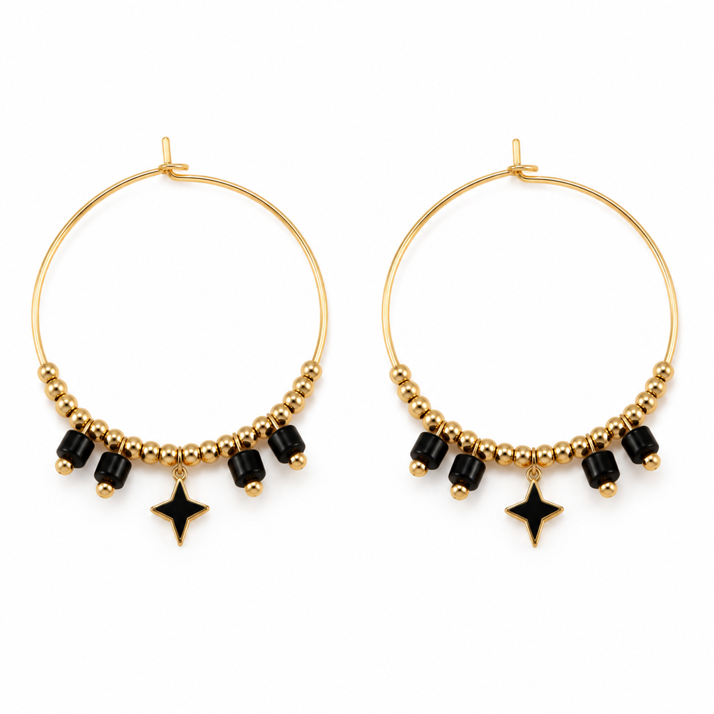 Pair of women's boho gold hoop earrings with black cylinder beads and dangling four-point black star charms on white background
