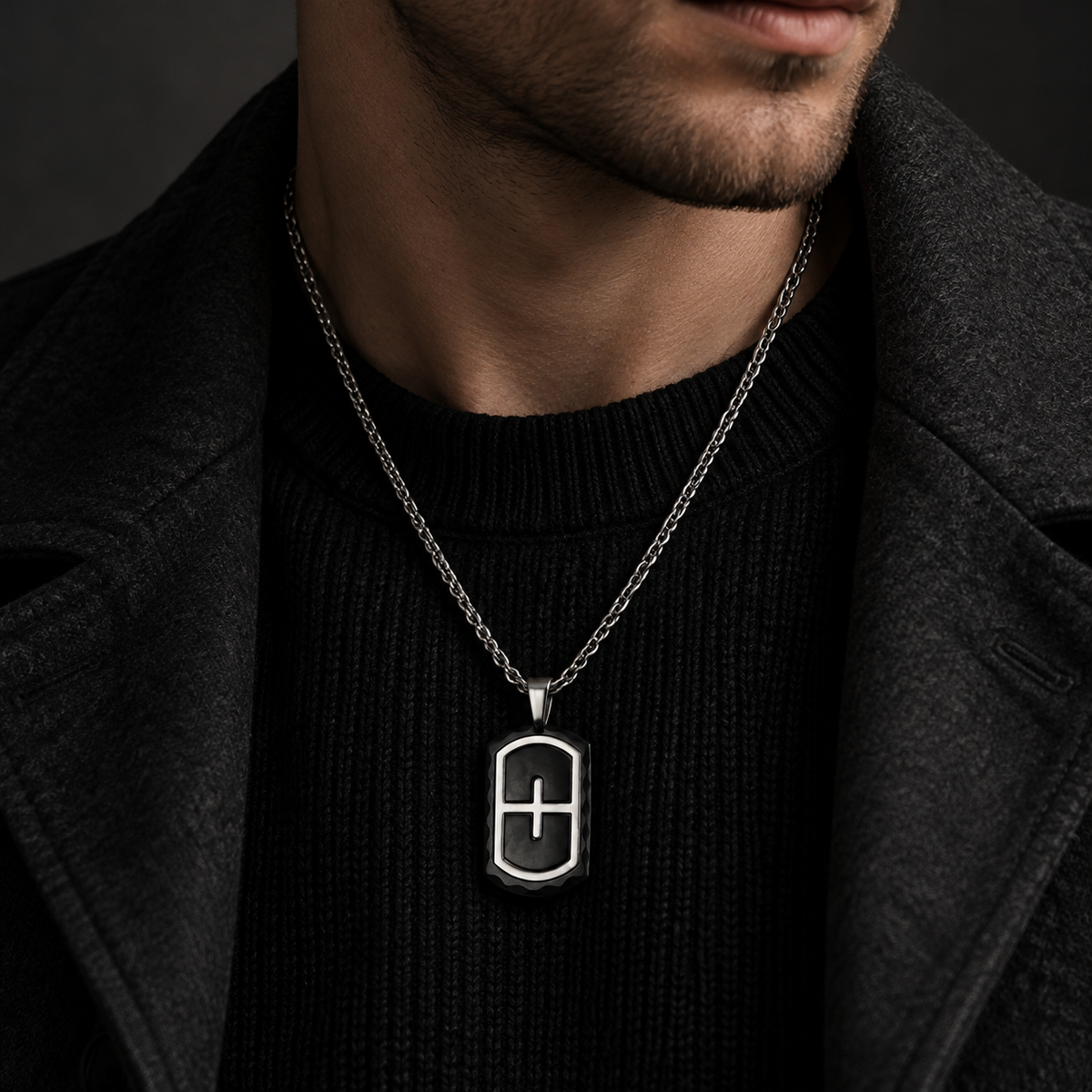 Model wearing men's two-tone steel cross shield dog tag on dark ribbed knit sweater
