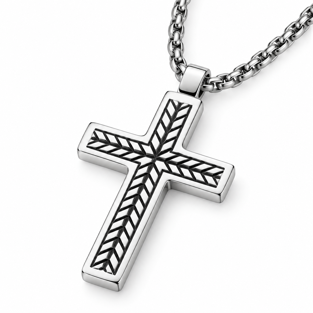 Angled studio close-up of men's engraved chevron stainless steel cross pendant on white background
