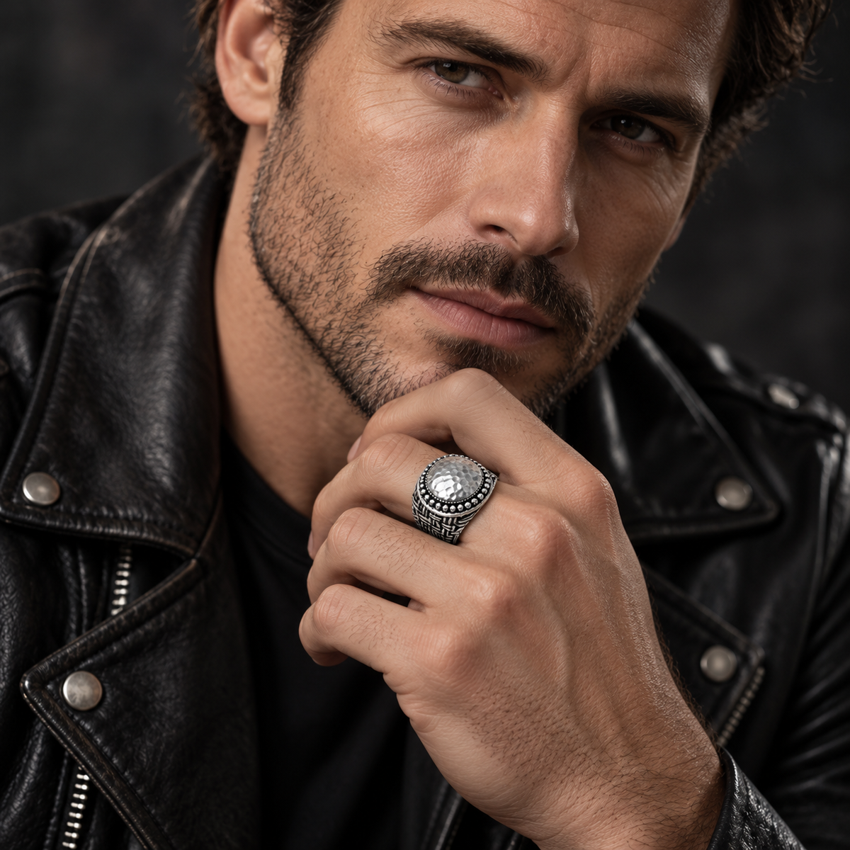 Close-up of male model wearing heavy Balinese hammered dome signet ring in leather jacket
