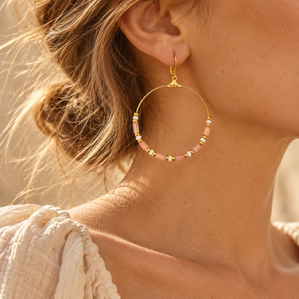 Close-up profile of model showcasing oversized gold hoop earrings with delicate pink beads against natural skin tone
