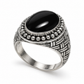 A silver-toned signet ring featuring a large, smooth oval black onyx stone in a detailed, textured basketweave setting with a border of small silver beads.